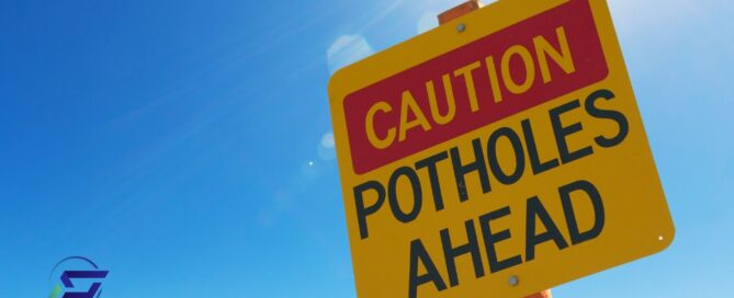 Sign that reads Caution Potholes Ahead